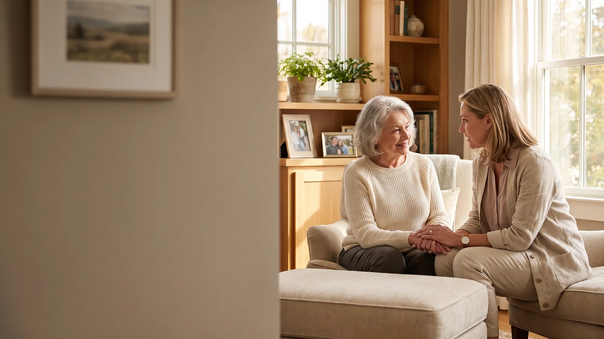 A caregiver sharing a warm conversation with an older adult in a sunlit home